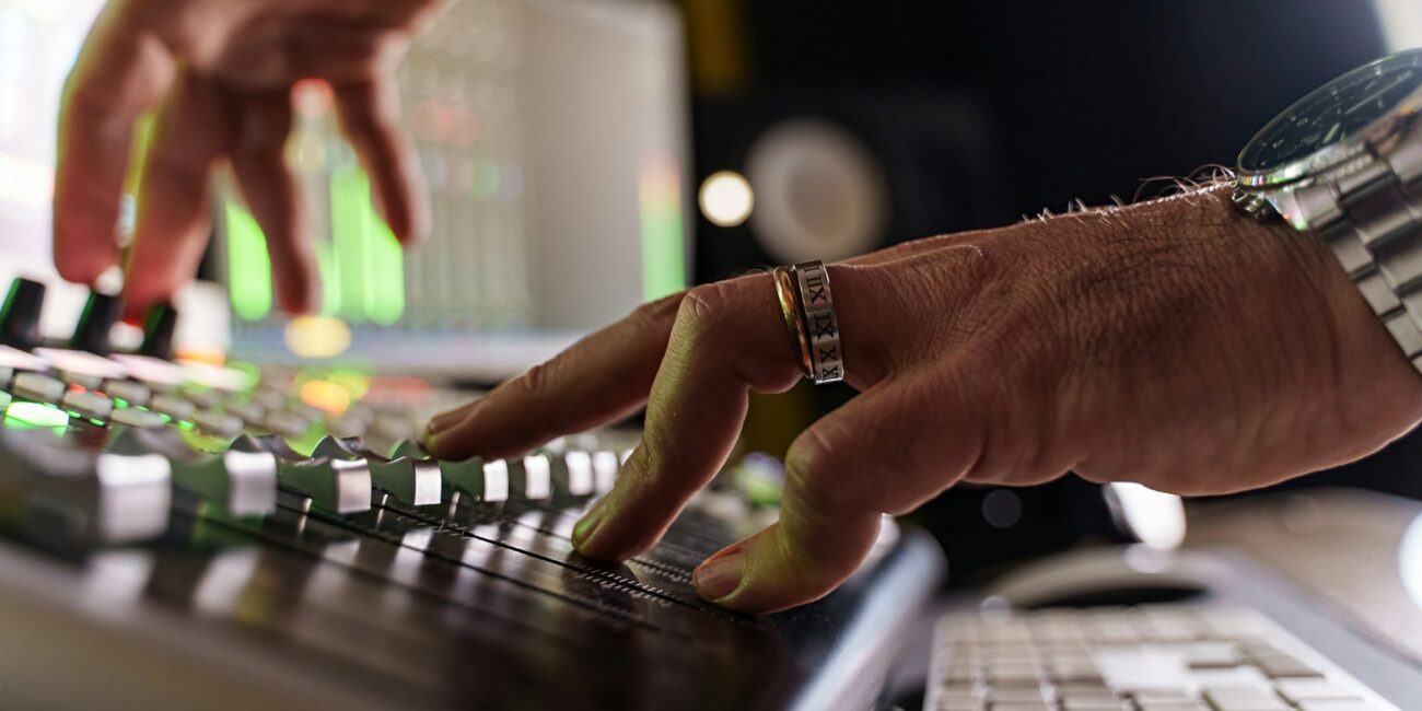 Close-up of caucasian music producer fading volume on sound mixer control panel